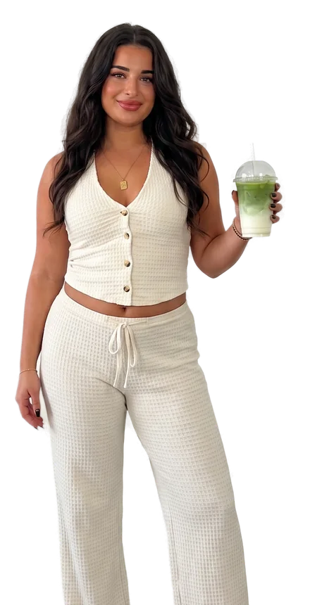 Anastasia lächelt in die Kamera und hält einen Matcha Latte mit Strohhalm hoch.
